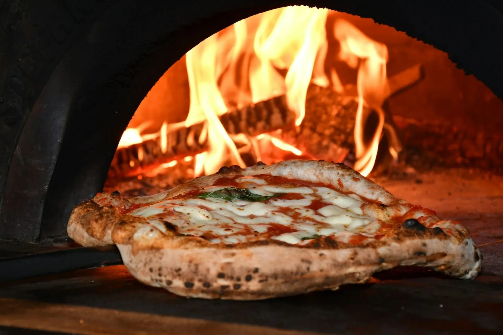 A wood-fired pizza fresh from a blazing oven