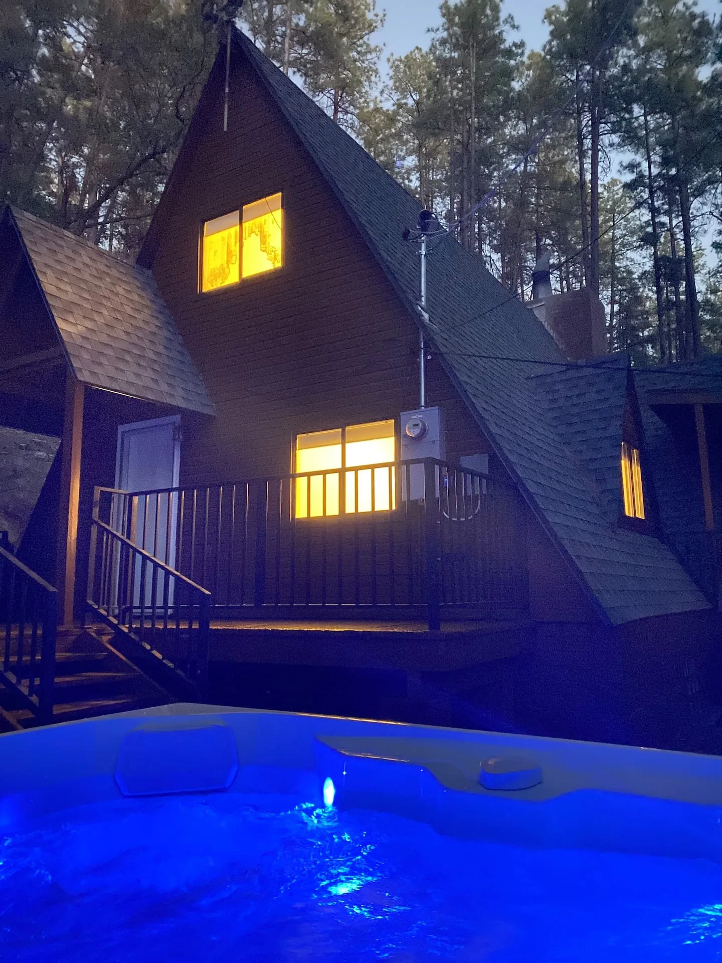 Warm cabin windows glowing at dusk in the forest